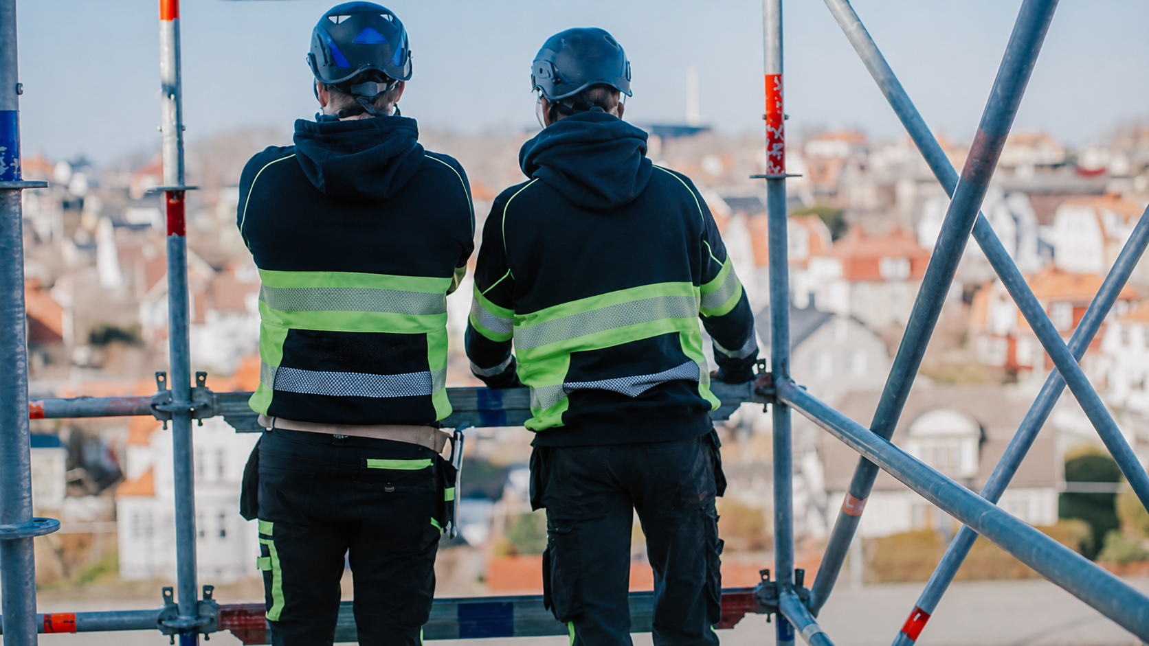 Ställningsbyggare i varselkläder och skyddshjälmar på byggnadsställning